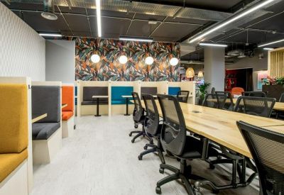 Open-plan coworking area with long wooden tables and colorful privacy booths.
