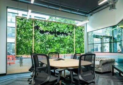 Bright meeting room featuring a live green wall and modern mesh chairs.