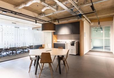 Communal breakout area with a white table, modern chairs, and industrial ceiling.