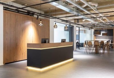 Minimalist reception desk with a wood-panelled wall and warm integrated lighting.