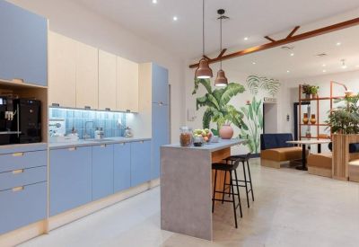 Modern communal kitchen and breakfast bar with blue cabinetry and tropical leaf wall mural.