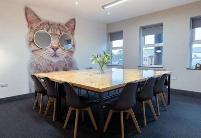 Meeting room with a large wooden table and a giant wall mural of a cat wearing sunglasses.