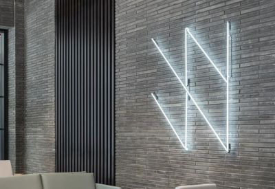 Modern lounge area featuring a grey brick accent wall and a blue neon light installation.