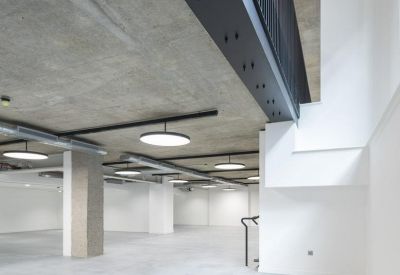 Large open-plan floor with exposed concrete ceilings and modern circular lighting.