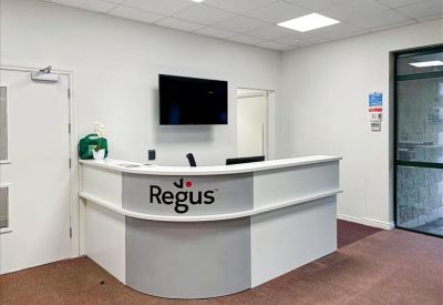 Modern reception desk with the company logo and a wall-mounted screen.