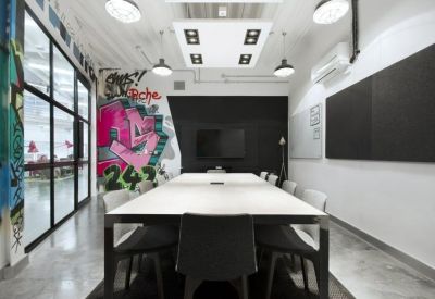 Modern meeting room featuring a white boardroom table and colorful graffiti wall art.