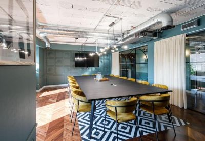Meeting room with a long black table, yellow chairs, and a striking geometric patterned rug.