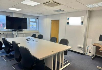 Professional meeting room featuring a large table, black chairs, and a wall-mounted flat-screen television.