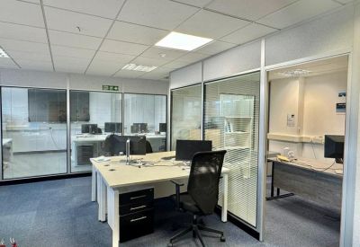 Private office suite featuring a central workstation with black ergonomic chair and glass-walled partitions.