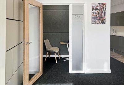 Private glass-walled phone booth or small meeting pod with a single chair and desk.
