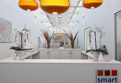 Bright white reception desk with modern orange light fixtures and orchids.
