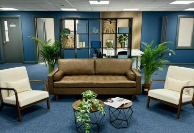 Spacious lounge area with a leather sofa, white armchairs, and blue feature walls.