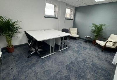Bright internal office suite with two white desks and potted plants.