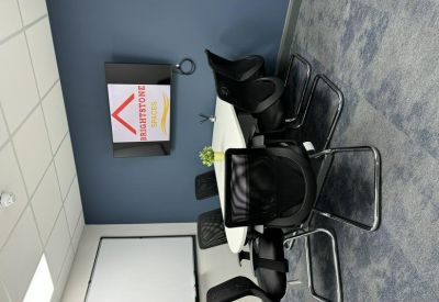 Meeting room with a white table and black mesh chairs against a blue wall.