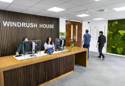 Wooden reception desk with two staff members and a branded feature wall.