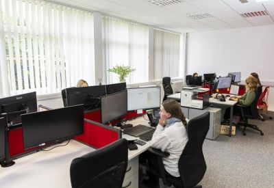 Bright open-plan office with multiple workstations and natural light from large windows.