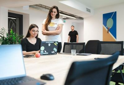 Modern meeting room featuring a laptop with stickers and views of a teammate.