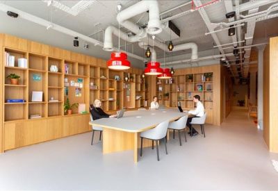 Communal library-style workspace with wood shelving and red pendant lights.