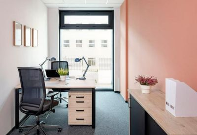 Private two-person office suite with ergonomic chairs and a coral-colored accent wall.