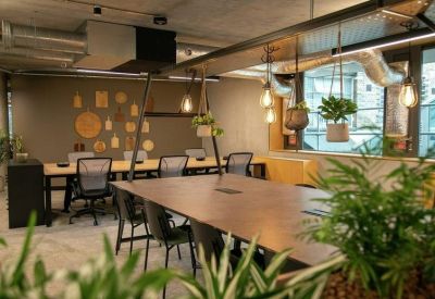 Collaborative workspace with wooden tables, indoor plants, and exposed ceilings.