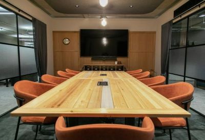 Large boardroom featuring a long wooden table and orange leather chairs.