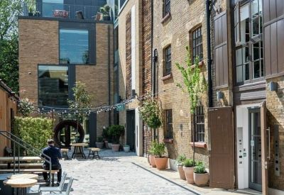 Industrial-style building exterior with a cobblestone walkway and potted plants.