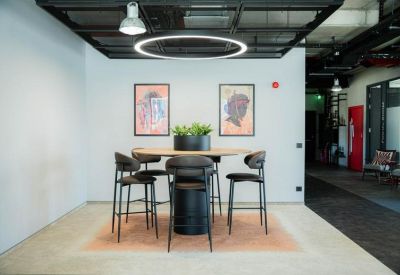 Minimalist breakout space with a round high-top table and framed art on a white wall.