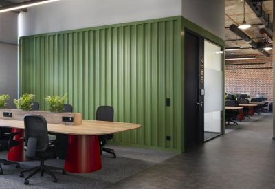 Modern coworking area with a long wooden table and green ribbed feature wall.