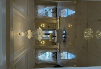 Reflection on a glossy floor showing a chandelier and white-curtained windows.