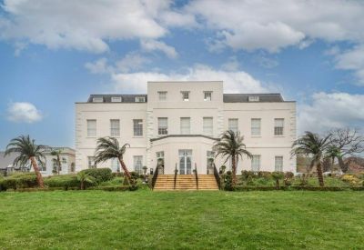 Exterior view of the white building facade from a grassy lawn with palm trees.