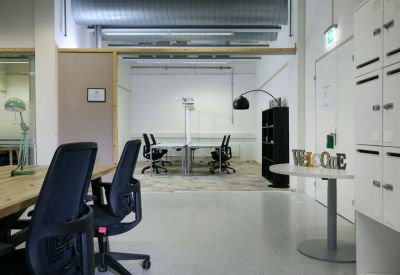 Bright reception area with white storage lockers, a round welcome table, and meeting room in the background.
