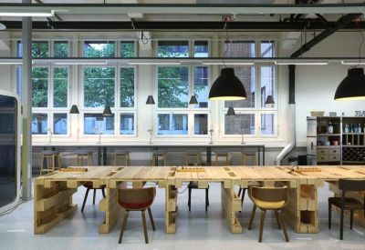 Long communal wooden workspace with modern seating and black pendant lighting.