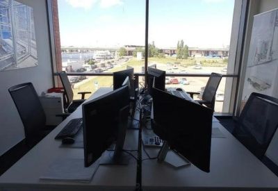 Four-person workstation cluster with dual monitors and a large window view.