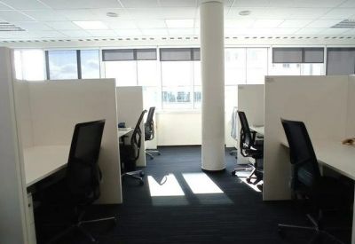 Quiet office area with cubicle-style white partitions and black mesh chairs.