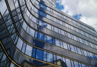 Dramatic low-angle exterior view of the curved glass facade at Zebra Tower, 1 Mokotowska Street.