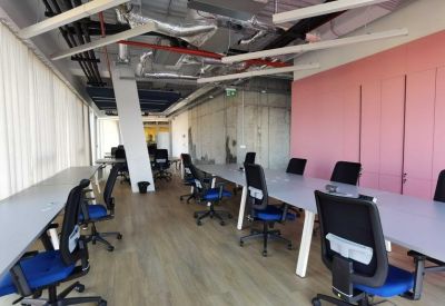 Long workstation rows with blue chairs and a pink feature wall.