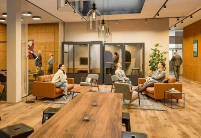 Lounge area with leather sofas, hanging glass pendant lights, and soundproof phone booths.