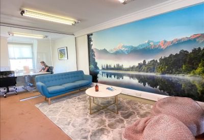 Lounge area with a blue sofa, bean bags, and a wall-to-wall landscape mural.