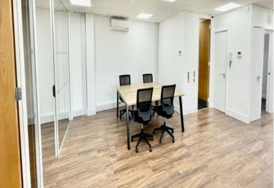Modern private office suite with glass partitions and four workstations.
