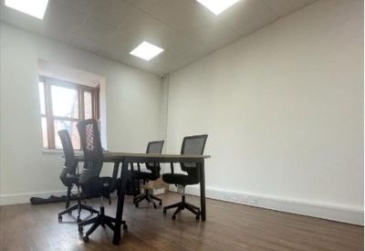 Bright four-person meeting room with large windows and hardwood flooring.