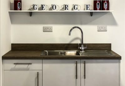 Compact kitchenette with dark wood countertops, stainless steel sink, and white cabinetry.