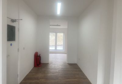 Long corridor with a fire extinguisher and wooden flooring.