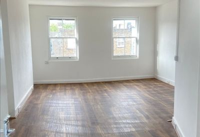 Spacious office area with wooden floors and fluorescent lighting.