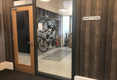Indoor bicycle storage area behind a glass wall with wooden wall paneling.