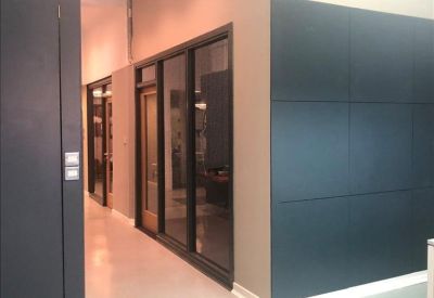 Modern office corridor featuring glass partitions and dark accent walls.