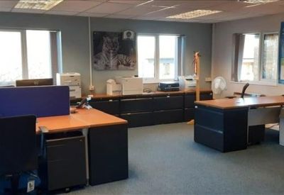 Brightly lit open-plan office with multiple workstations and blue partitions.