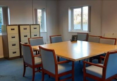 Small meeting room with a central wooden table and blue upholstered chairs.