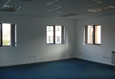 Empty office suite with blue carpeting and three windows overlooking the street.