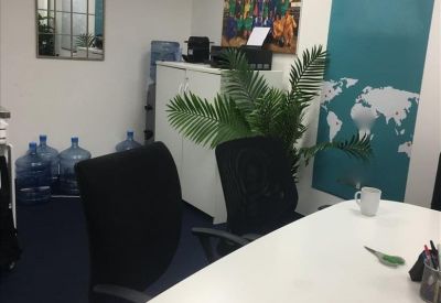 Professional meeting room with a large white table, teal accent wall, and world map graphic.