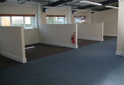 Spacious office area featuring blue carpeted walkways and white half-height dividers.